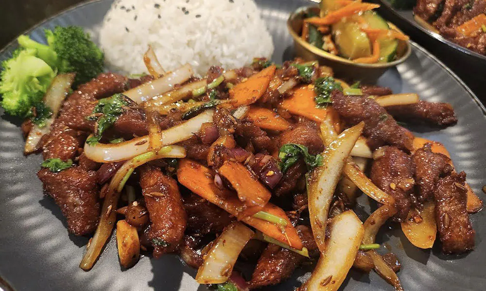Spicy stir-fried beef with onions, carrots, rice, and broccoli
